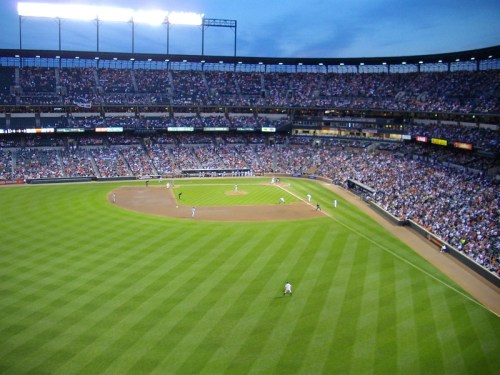 Aerial view of a packed baseball stadium during a game, with players on the field and fans in the stands.
