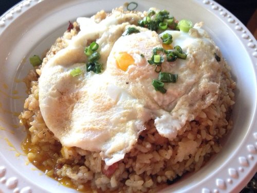 A bowl of fried rice topped with two sunny-side-up eggs and green onions.