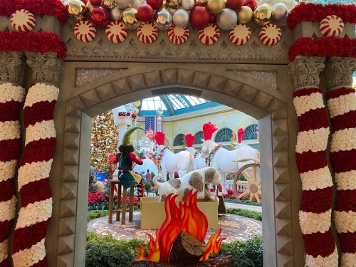 A festive holiday display featuring white horses, a Christmas tree, and red and white decorations in a vibrant setting.