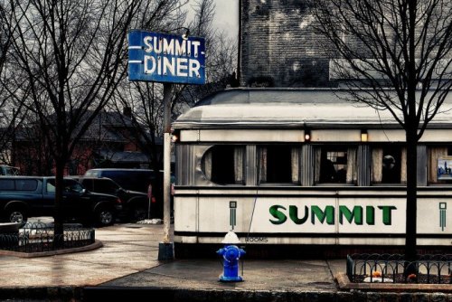 A vintage diner with a blue sign reading "Summit Diner," surrounded by bare trees and parked cars.
