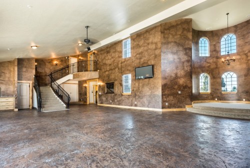 Spacious interior with textured walls, large windows, and a staircase leading to an upper level. Modern and well-lit.