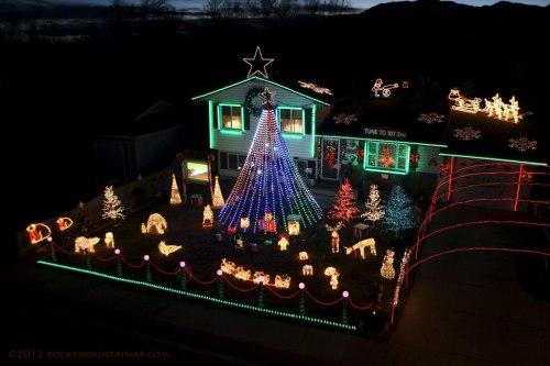 A brightly lit house decorated for the holidays, featuring a large colorful tree and various festive light displays.