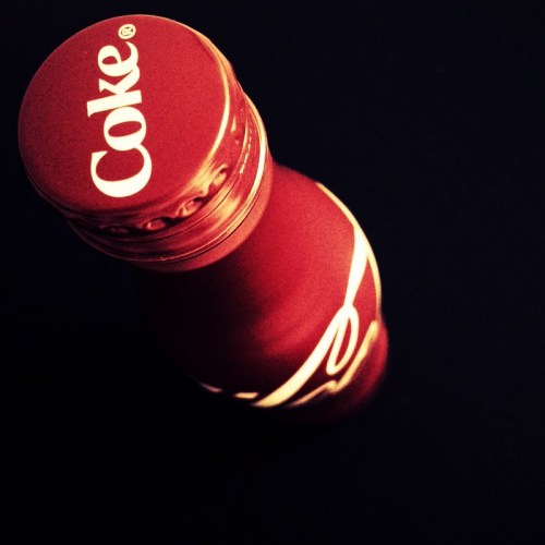 A top view of a red Coca-Cola bottle with the logo prominently displayed on the cap.