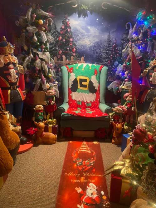 A festive Christmas scene with a decorated chair, nutcrackers, trees, and holiday decorations.