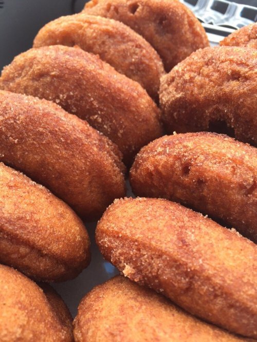 A close-up of freshly fried, golden-brown donuts with a crispy exterior, arranged closely together.