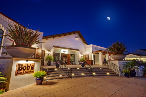 Exterior of Bob's restaurant at night, featuring steps, potted plants, and a moonlit sky.