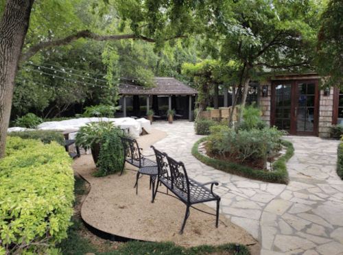 A serene garden path with benches, surrounded by greenery and a cozy gazebo in the background.