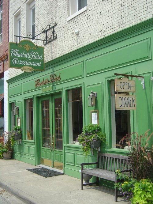A green building with a sign reading "Charlotte Hotel & Restaurant" and an "Open for Dinner" sign outside.