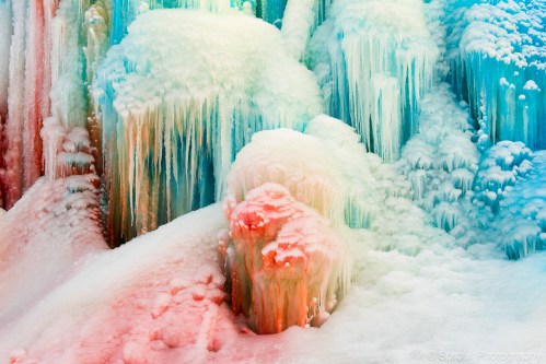 Colorful ice formations with vibrant hues of blue, green, and red, creating a stunning winter landscape.