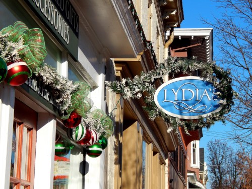 A storefront with a sign reading "Lydia's," decorated with festive greenery and ornaments.