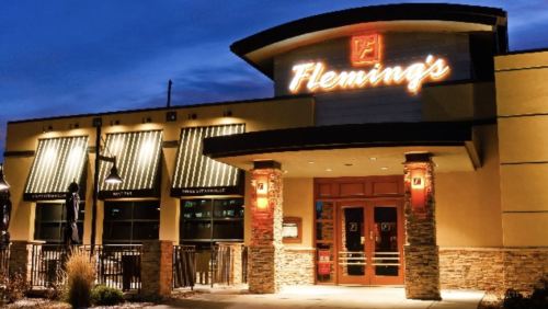 Exterior of Fleming's restaurant at night, featuring a lit sign and modern architecture.