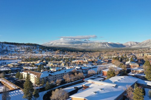 Aerial view of a snowy town surrounded by mountains under a clear blue sky.
