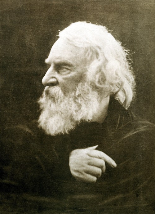 A sepia-toned portrait of an elderly man with a long white beard, gazing thoughtfully to the side.