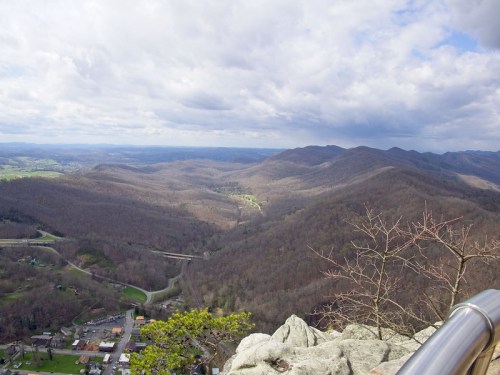 A panoramic view of rolling mountains and a valley under a cloudy sky, with a small town visible below.