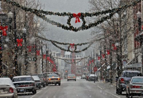 Snowy street decorated with festive wreaths and red bows, creating a cozy holiday atmosphere.