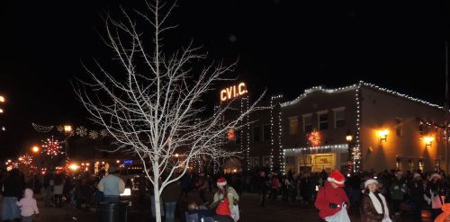 A festive night scene with a crowd gathered near a building adorned with holiday lights and decorations.
