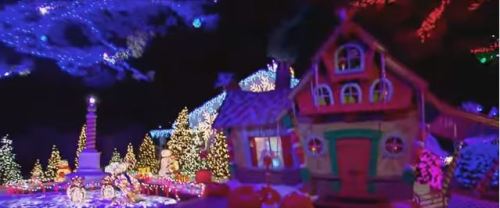A colorful holiday display featuring a whimsical house, decorated trees, and vibrant lights in a festive setting.