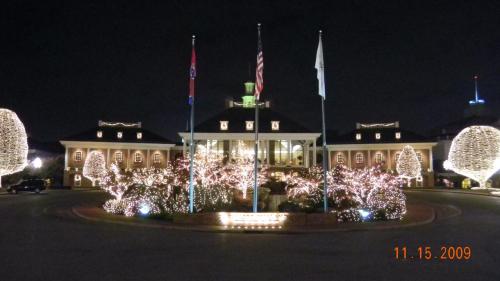 A beautifully lit building at night, surrounded by trees adorned with white lights and flags in front.