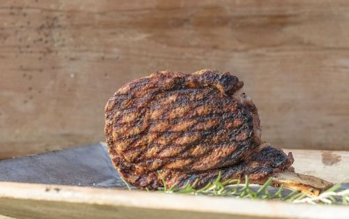 A perfectly grilled steak with a charred crust, resting on a wooden board with a hint of rosemary.