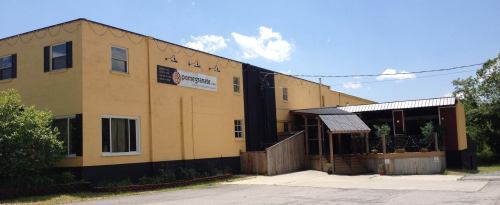 A large yellow building with a black section, featuring a sign and a covered entrance, under a clear blue sky.