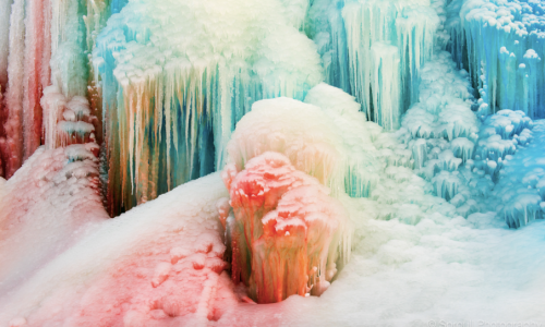 Colorful ice formations with vibrant hues of blue, green, and pink, creating a stunning winter landscape.