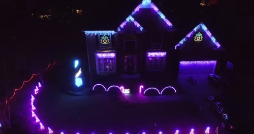 A house decorated with vibrant purple and blue lights, creating a festive atmosphere at night.