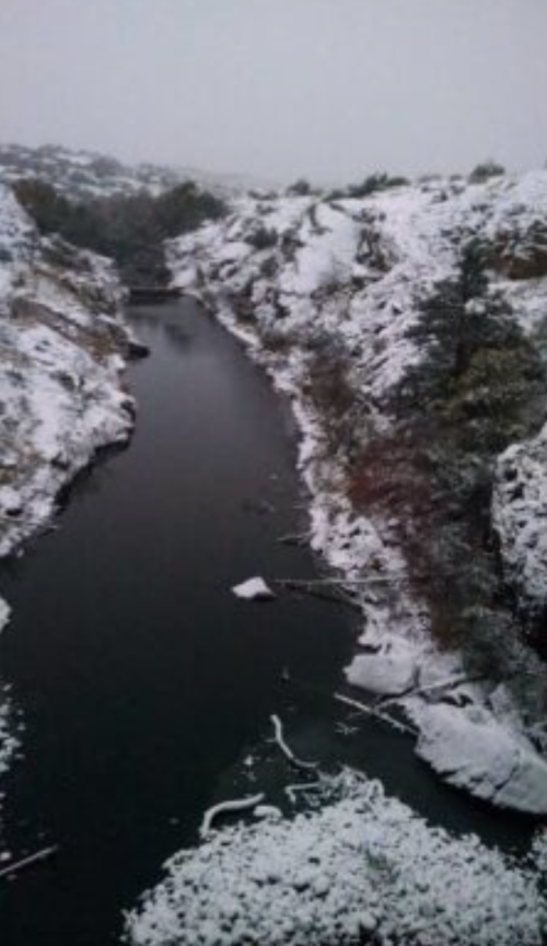 A snowy landscape with a winding river surrounded by snow-covered hills and trees.