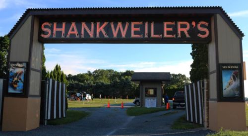 Entrance to Shankweilers, featuring a large sign and a view of the parking area and surrounding trees.