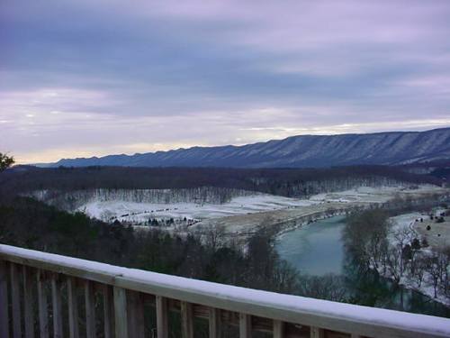 A scenic view of a snowy landscape with mountains in the background and a river winding through the valley.