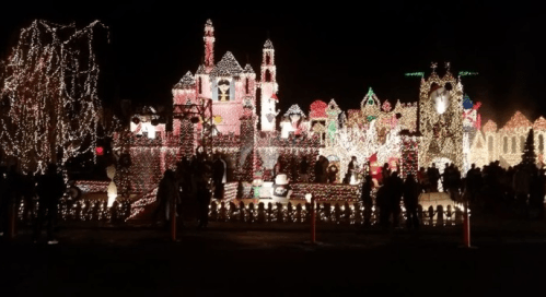A festive display of colorful Christmas lights illuminating a whimsical holiday scene with people admiring it.