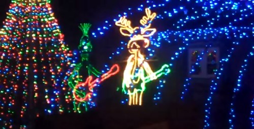 Colorful holiday lights display featuring a guitar-playing reindeer and a green figure with a guitar.