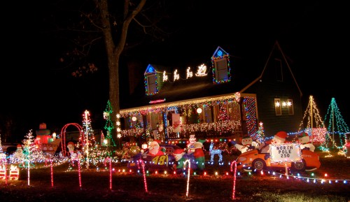 A brightly lit house decorated for Christmas with colorful lights, snowmen, and festive decorations in the yard.