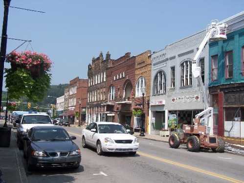 A street view of a small town with historic buildings, parked cars, and a lift working on a storefront.