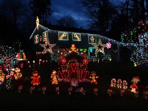 A festive house decorated with colorful Christmas lights, featuring candy canes, gingerbread figures, and stars.