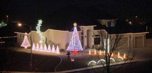 A beautifully decorated house at night, featuring colorful Christmas lights, a large tree, and festive displays.