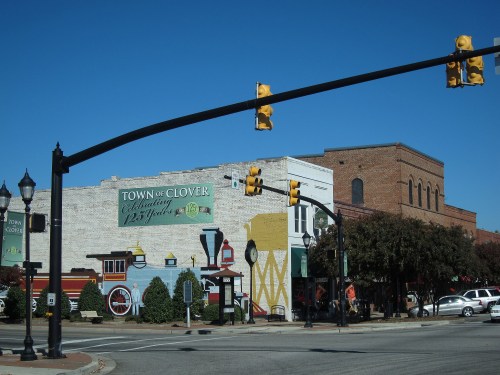 A street view of Clover, featuring a colorful mural and traffic lights against a clear blue sky.