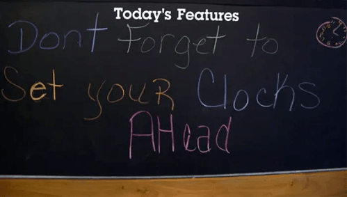 Chalkboard message reminding to set clocks ahead, with colorful text and a clock illustration in the corner.