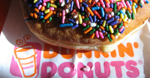 Close-up of a colorful donut with sprinkles on a Dunkin' Donuts napkin.