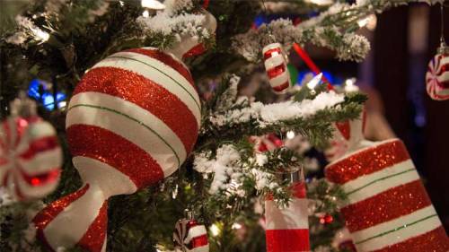 Close-up of a Christmas tree adorned with red and white striped ornaments and candy-themed decorations.