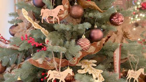 A decorated Christmas tree with horse-themed ornaments, ribbons, and red berries.