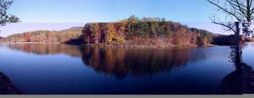 A serene lake surrounded by colorful autumn trees, reflecting the vibrant foliage on calm water.