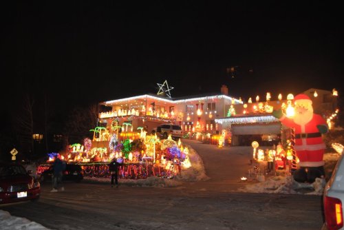A brightly lit house decorated with colorful Christmas lights and inflatable decorations, including Santa, at night.