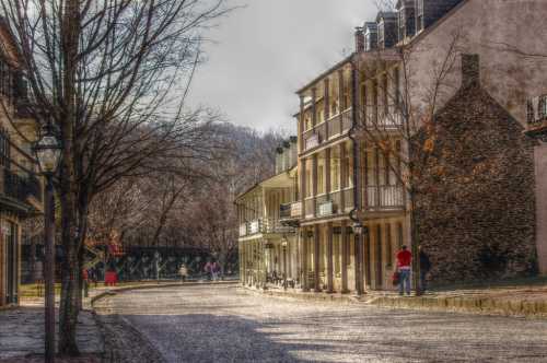 A quiet street lined with historic buildings, trees, and a distant bridge, bathed in soft, warm light.