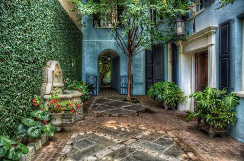 A serene courtyard with a stone fountain, lush greenery, and blue walls, creating a tranquil outdoor space.