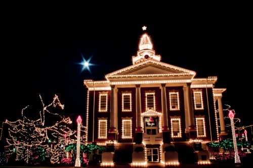 A beautifully lit historic building adorned with festive lights, surrounded by colorful decorations at night.