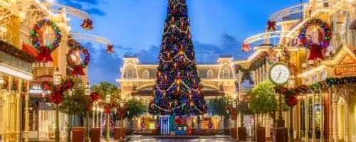 A festive street scene featuring a large decorated Christmas tree and holiday decorations in a charming town square.