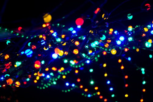 Colorful string lights in various hues of blue, red, green, and yellow, glowing against a dark background.