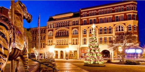 A festive scene featuring a decorated Christmas tree in front of a historic building, with a golden zebra statue nearby.