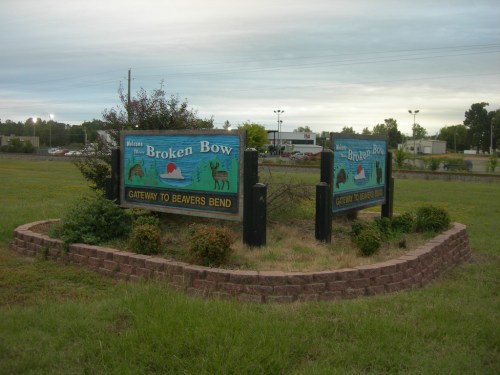 Sign for Broken Bow, Oklahoma, featuring a colorful design and the phrase "Gateway to Beavers Bend," surrounded by grass.