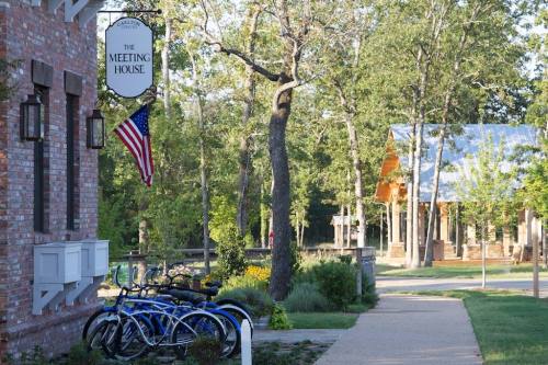 A scenic view of a brick building with a sign, American flag, and parked bicycles along a tree-lined path.